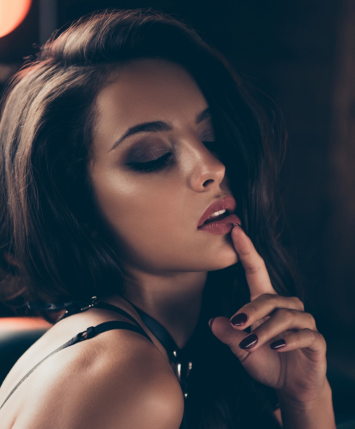 Woman with finger on lips, sultry gaze.