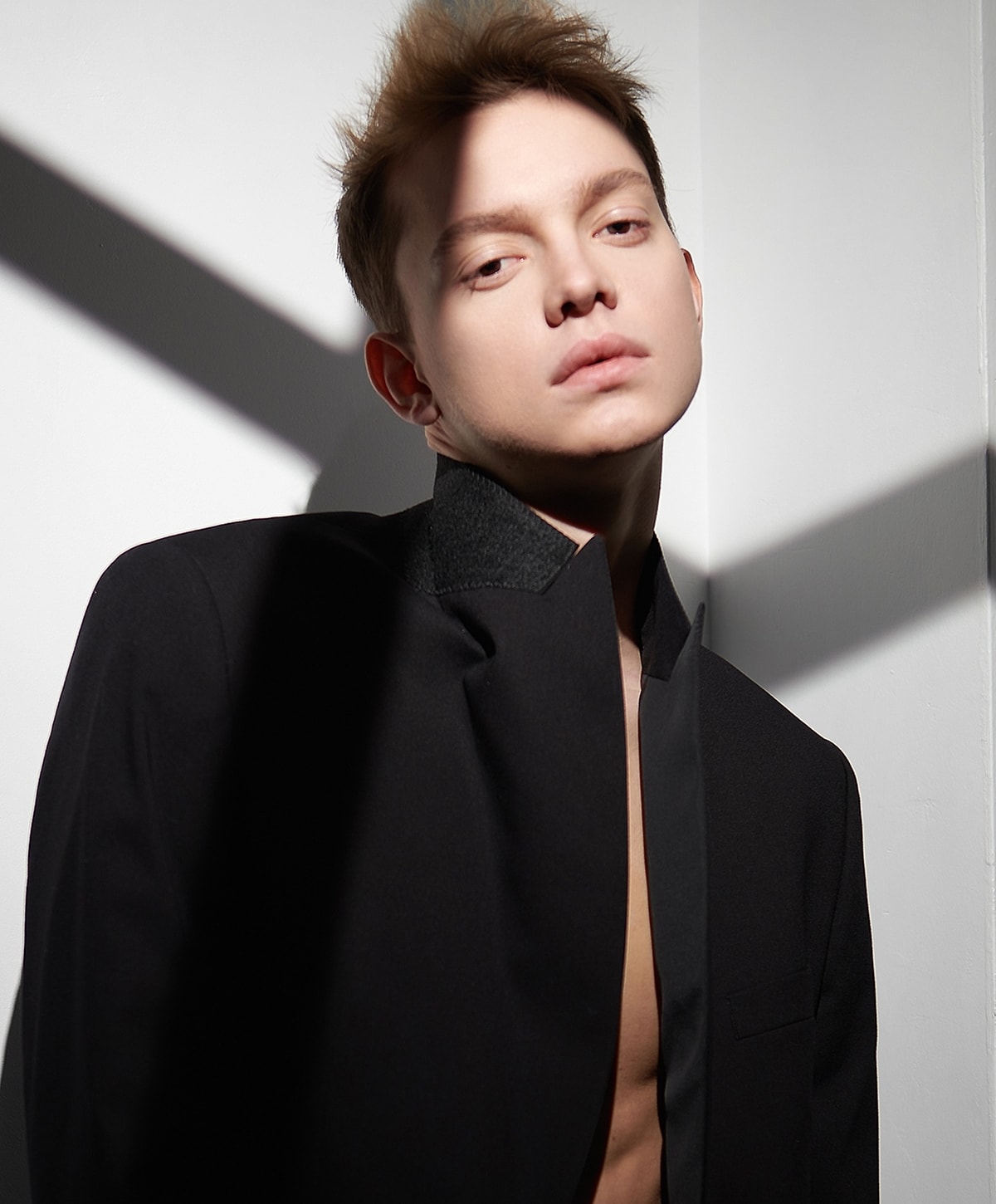 Model poses in stylish black outfit with shadows.