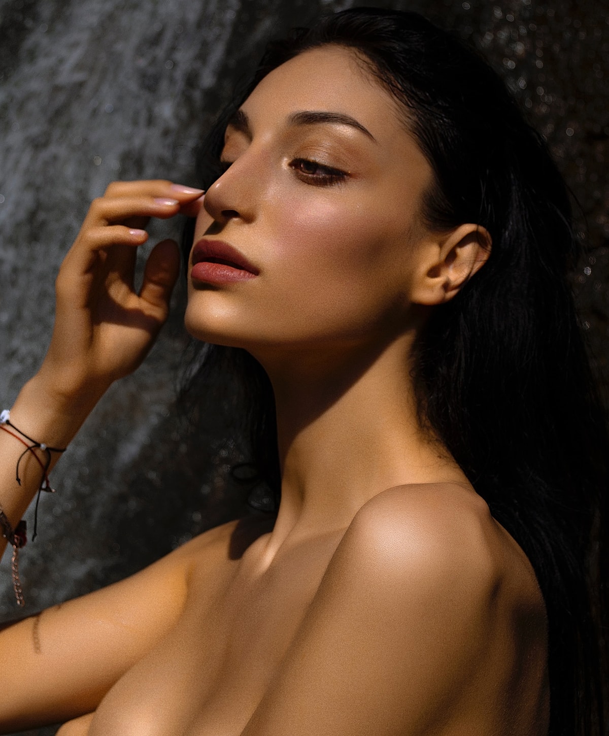 Close-up of woman by waterfall, serene expression.